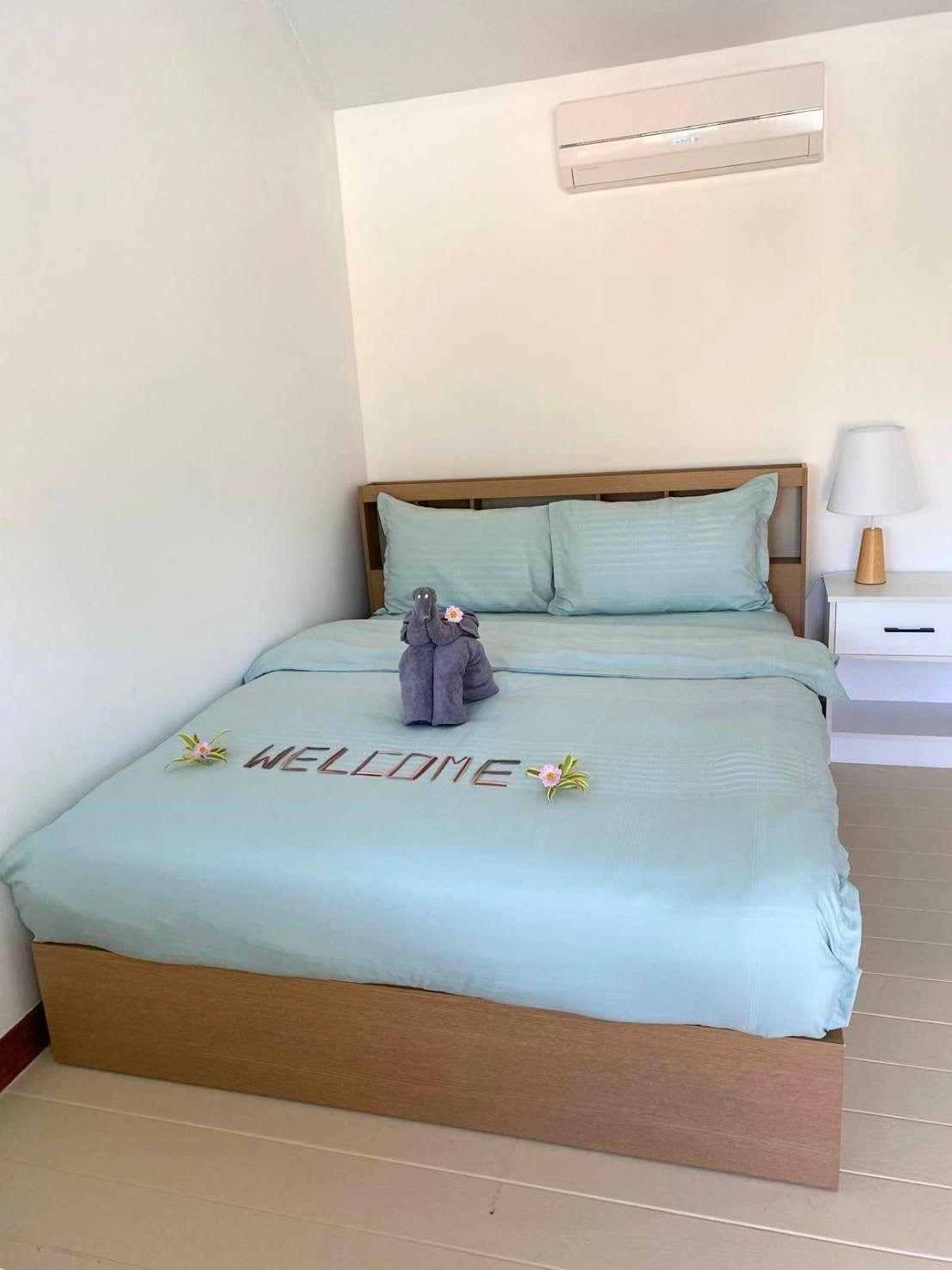 Queen bed made up with aqua linen and a towel elephant on a welcome note, in a bungalow at The White Room