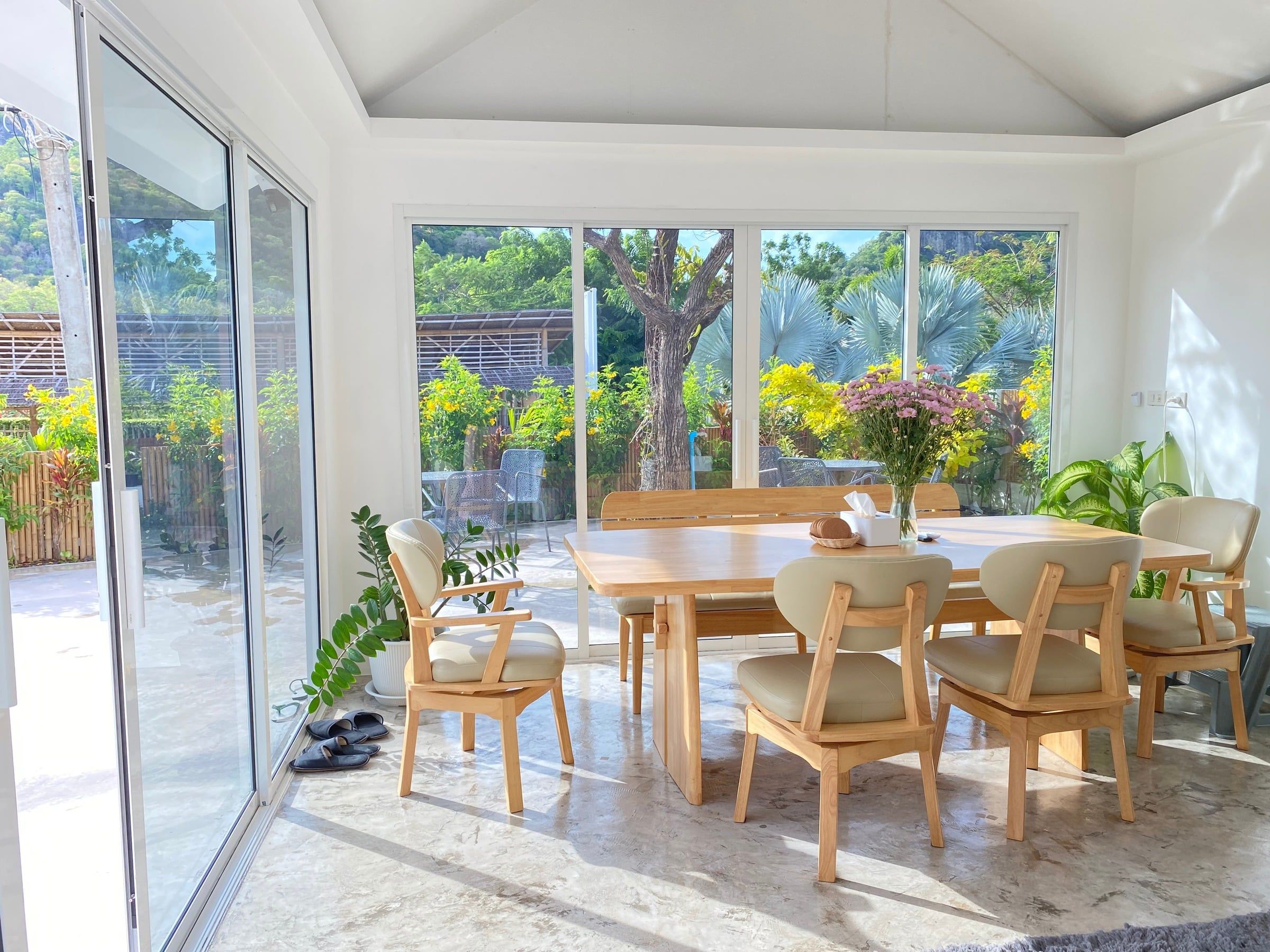Glass-walled dining room with an oak table and a view of the garden at The White Room