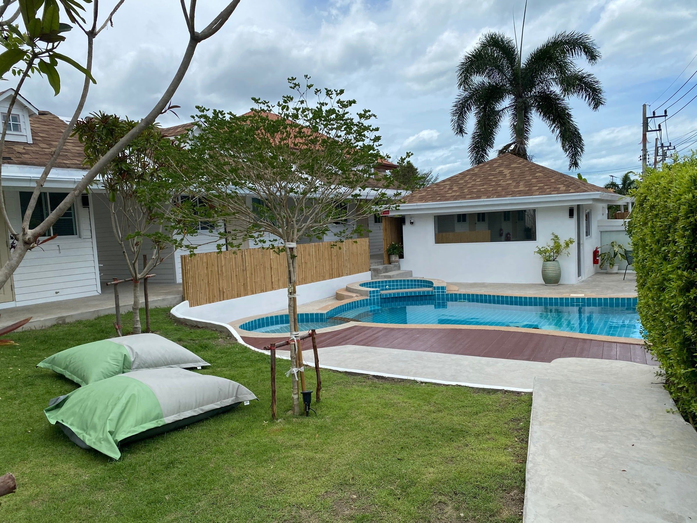 Green beanbags on the lawn beside the pool, with palms and the bungalows behind