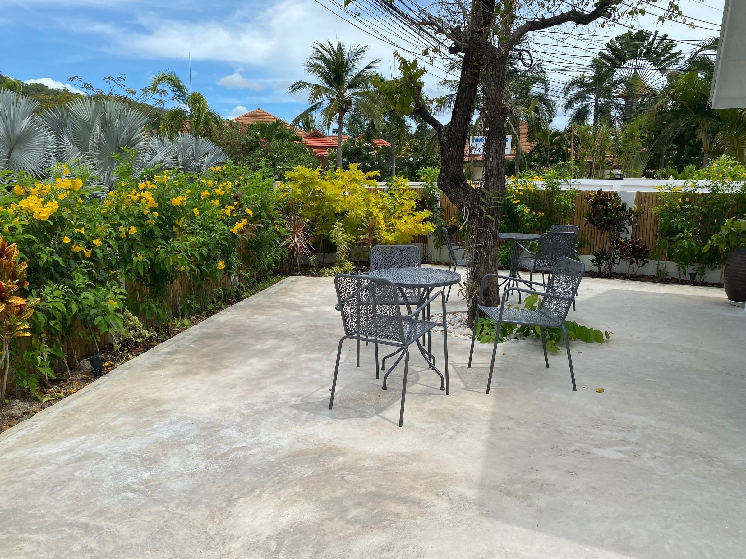 Patio with a metal table and chairs among flowering shrubs