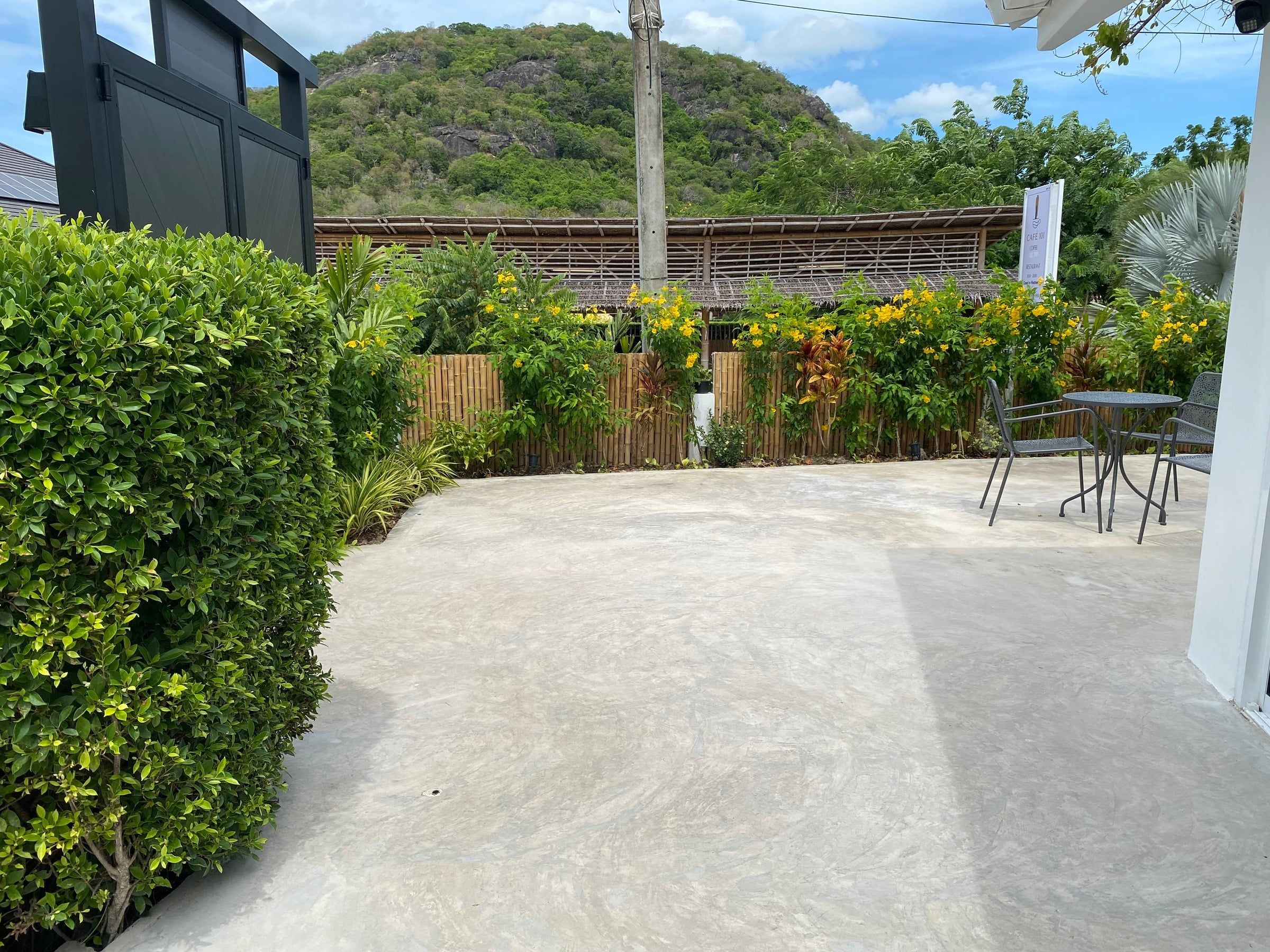 Open terrace beside a hedge, with a mountain behind