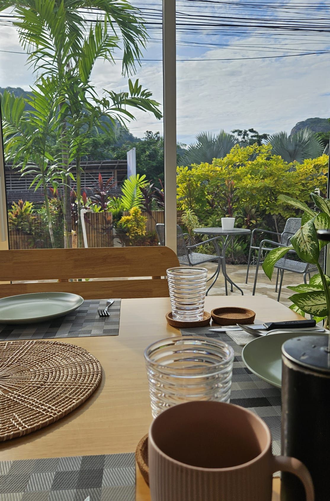 Breakfast table set with glasses and rattan placemats, looking onto a garden terrace and limestone hills at The White Room