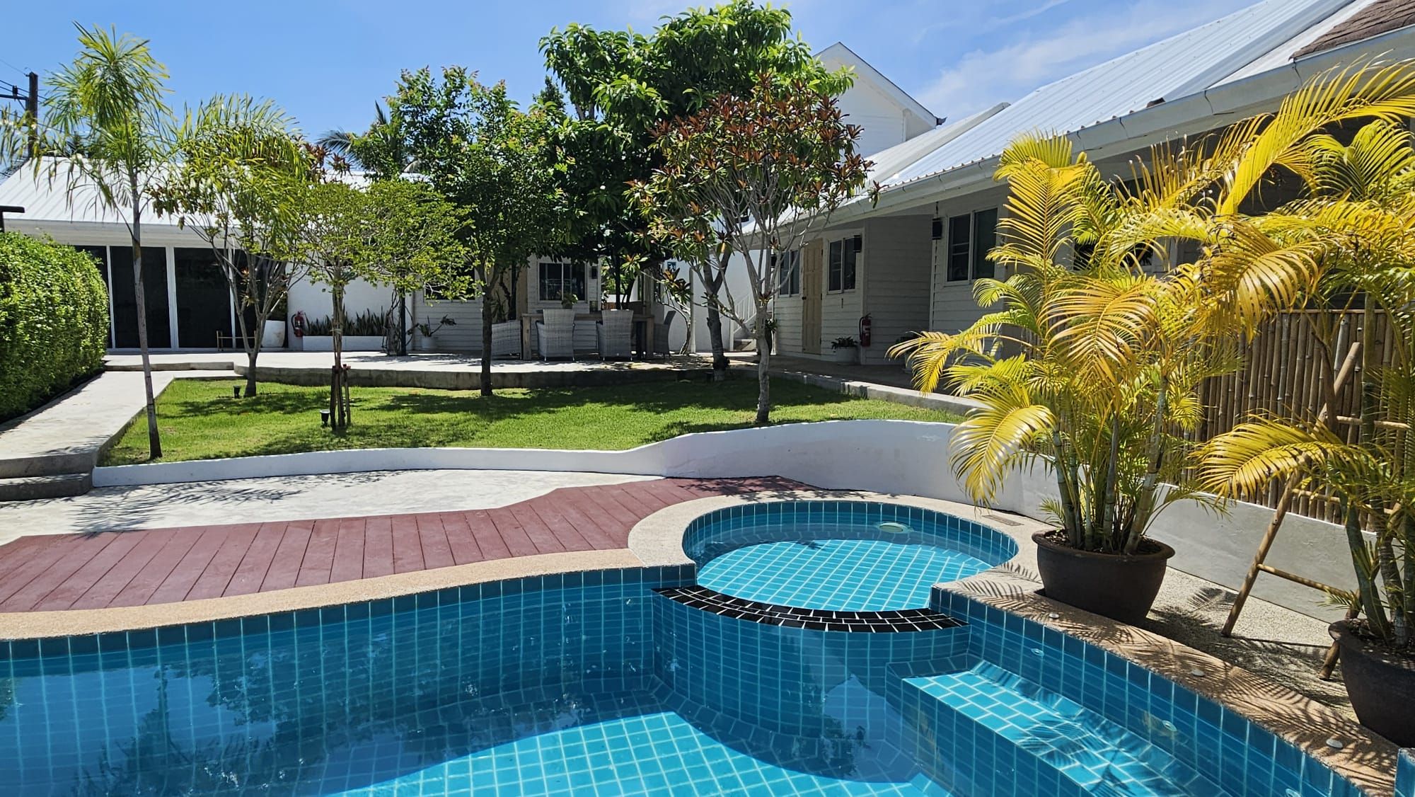 Swimming pool, lawn and palms in front of the white guest bungalows at The White Room, Hua Hin
